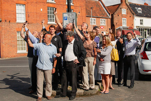 Members of Reepham's business community desperately seeking a mobile phone signal in Reepham Market Place. Photo: John Tym