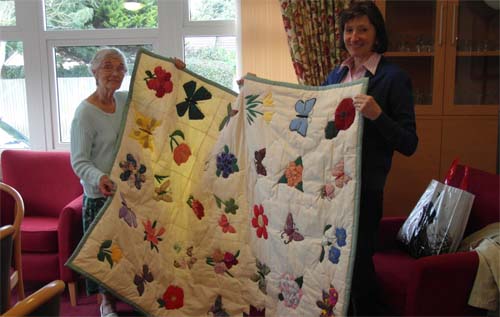 Rosina Harman (left) presents the quilt to Judith Rollestone